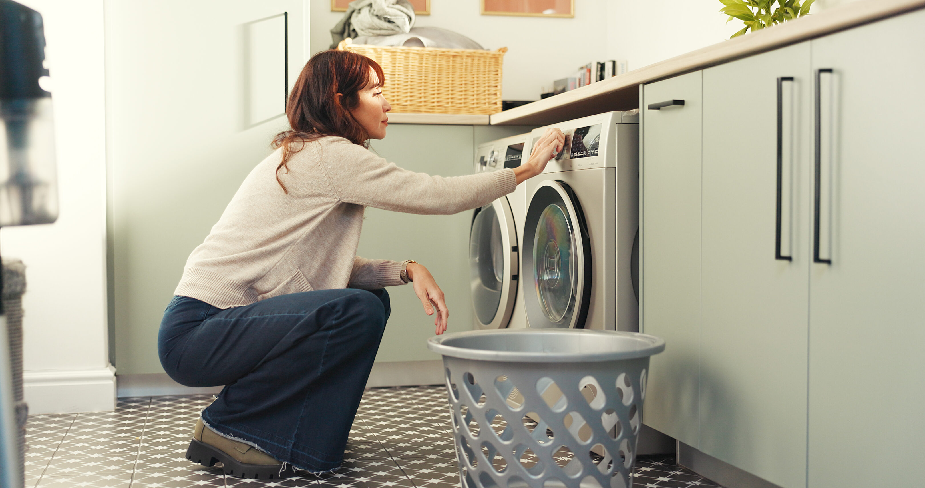 Woman using washing machine in laundry room